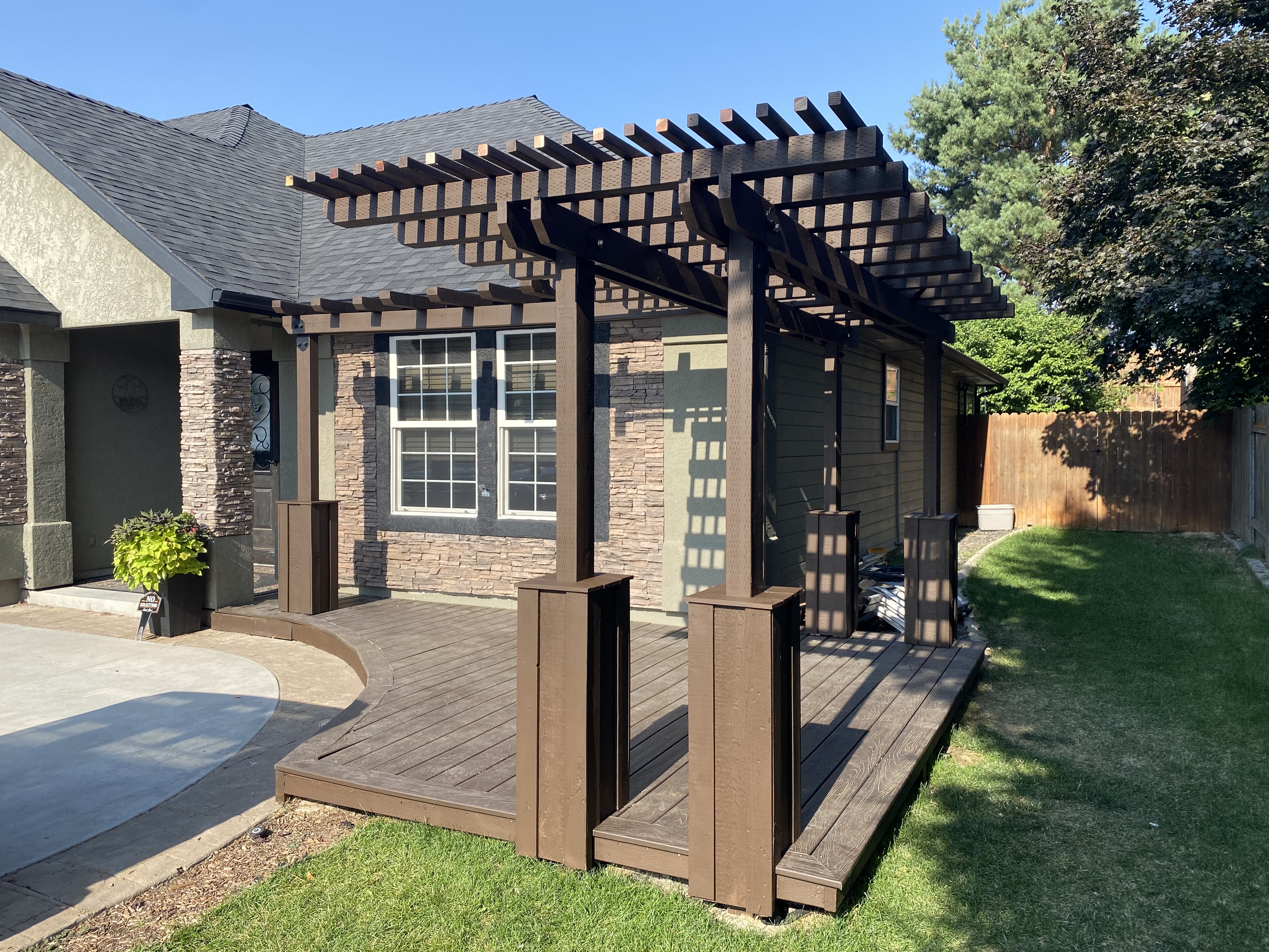 Finished brown deck with custom pergola on the front of a home