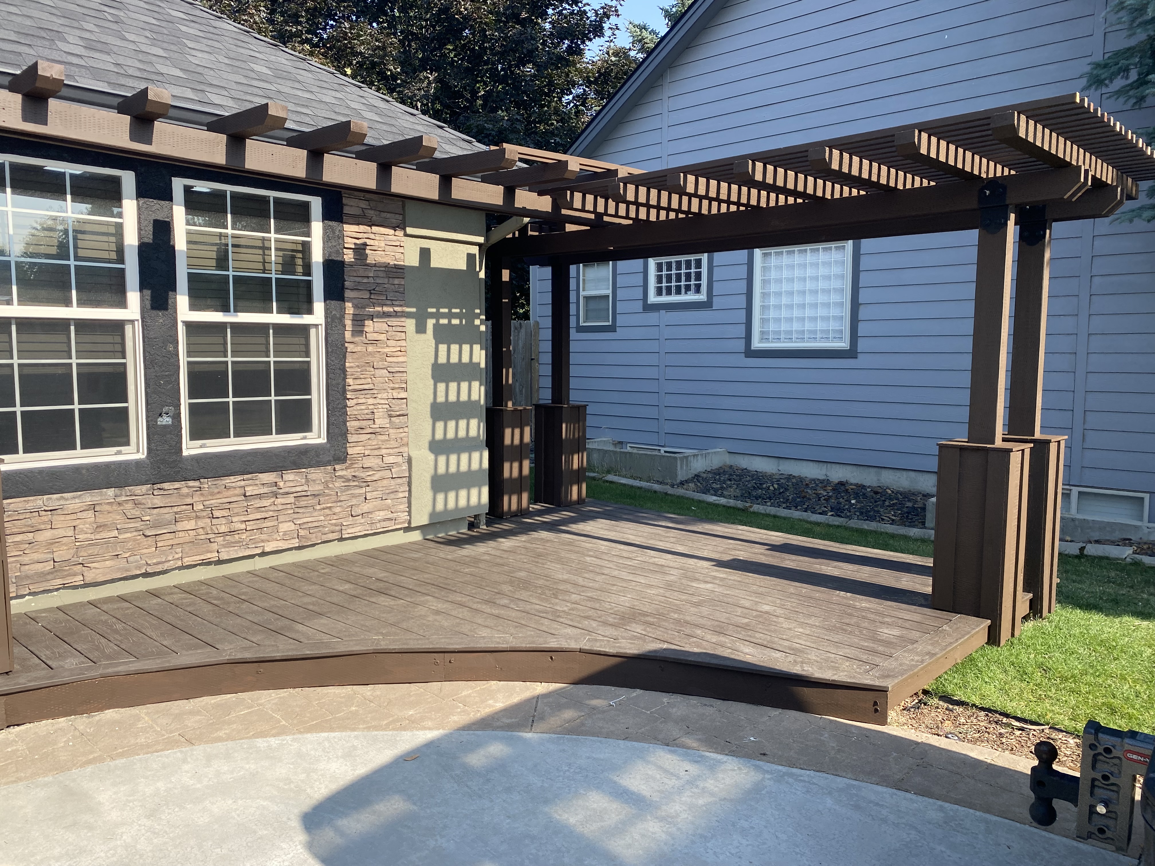 Side angle of brown deck with pergola and stamped concrete patio
