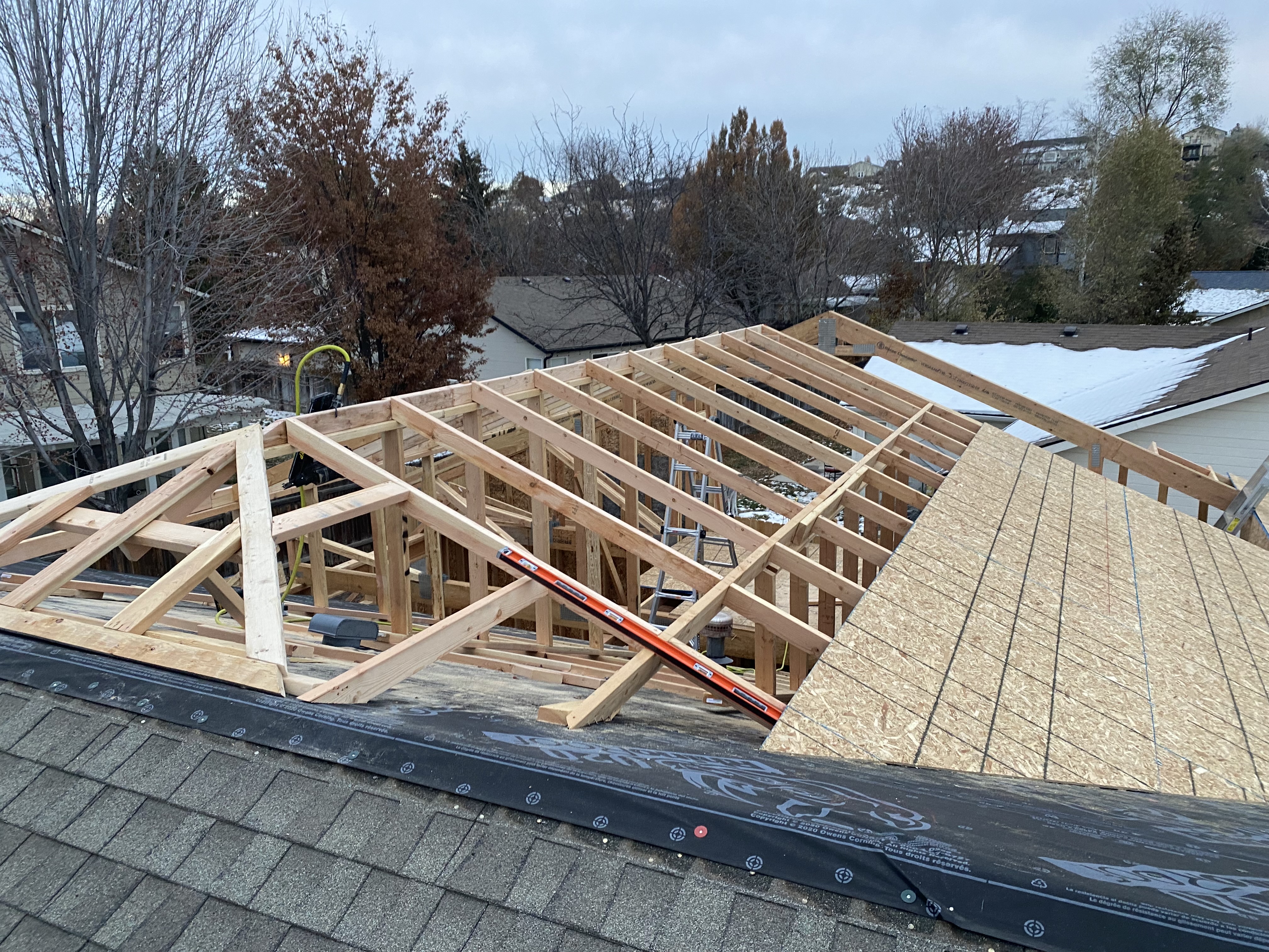 Roof addition framing in progress over existing home